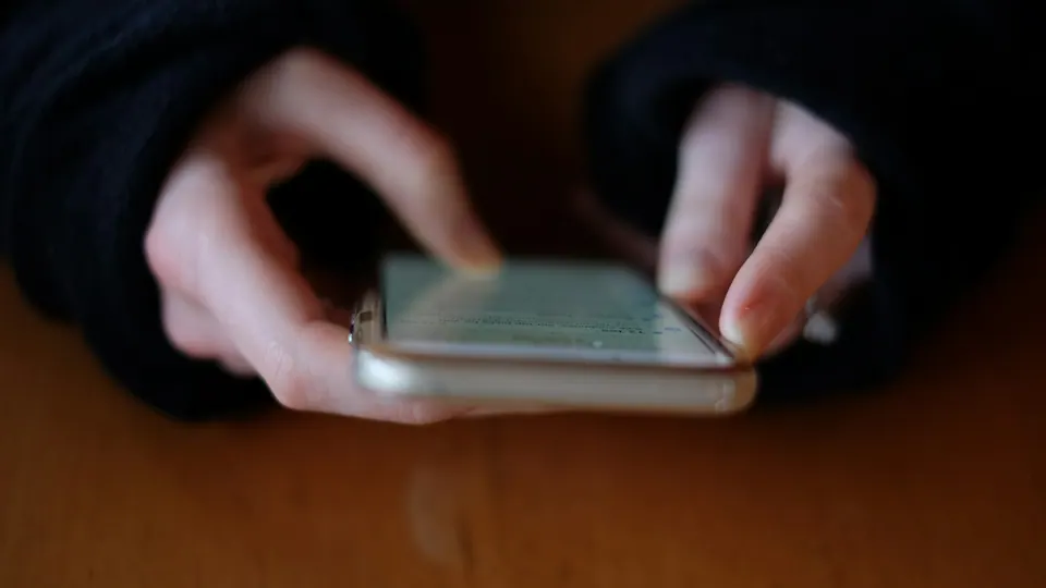 Mãos digitando perguntas no celular