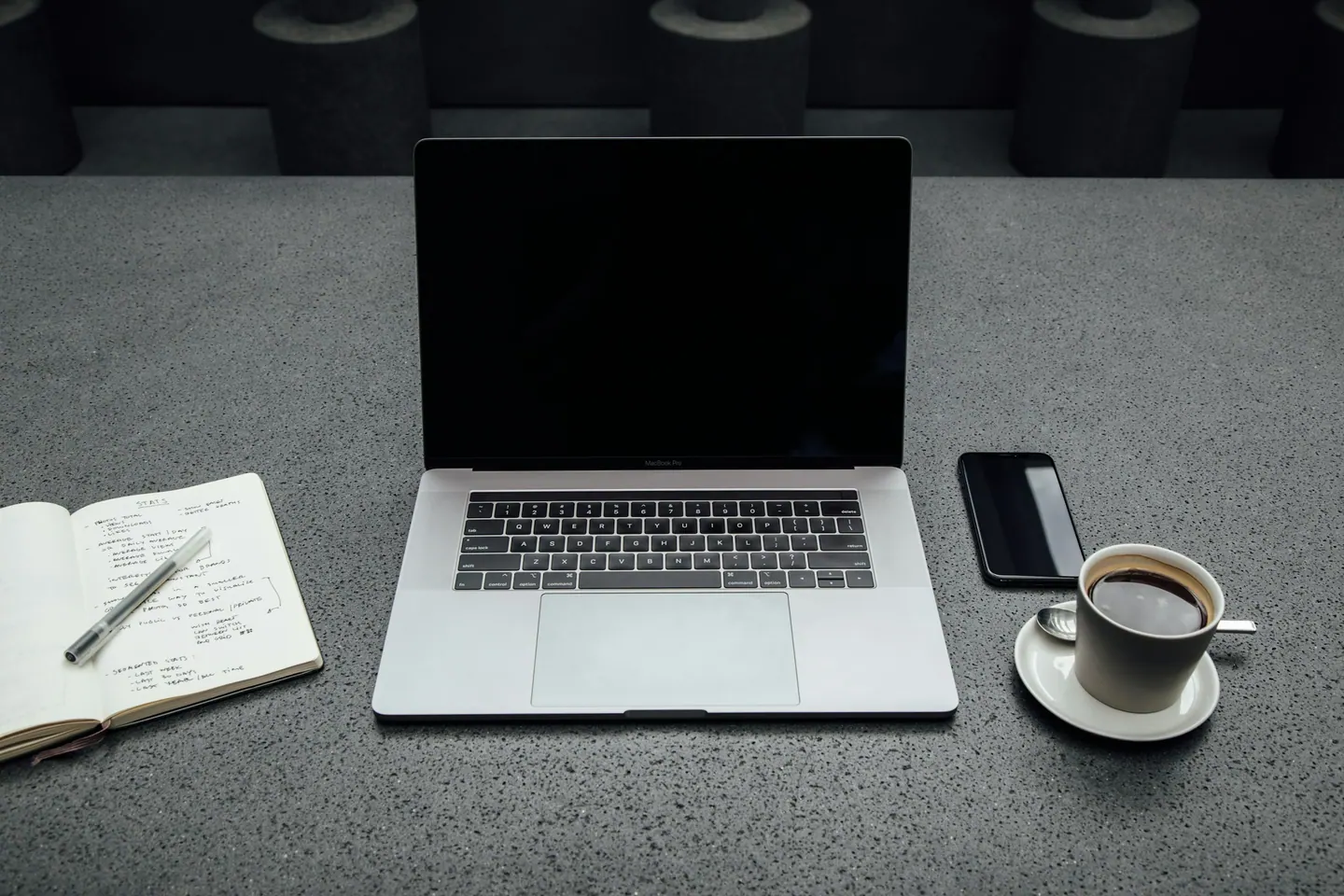 Notebook, caderno e xícara de café sobre a mesa