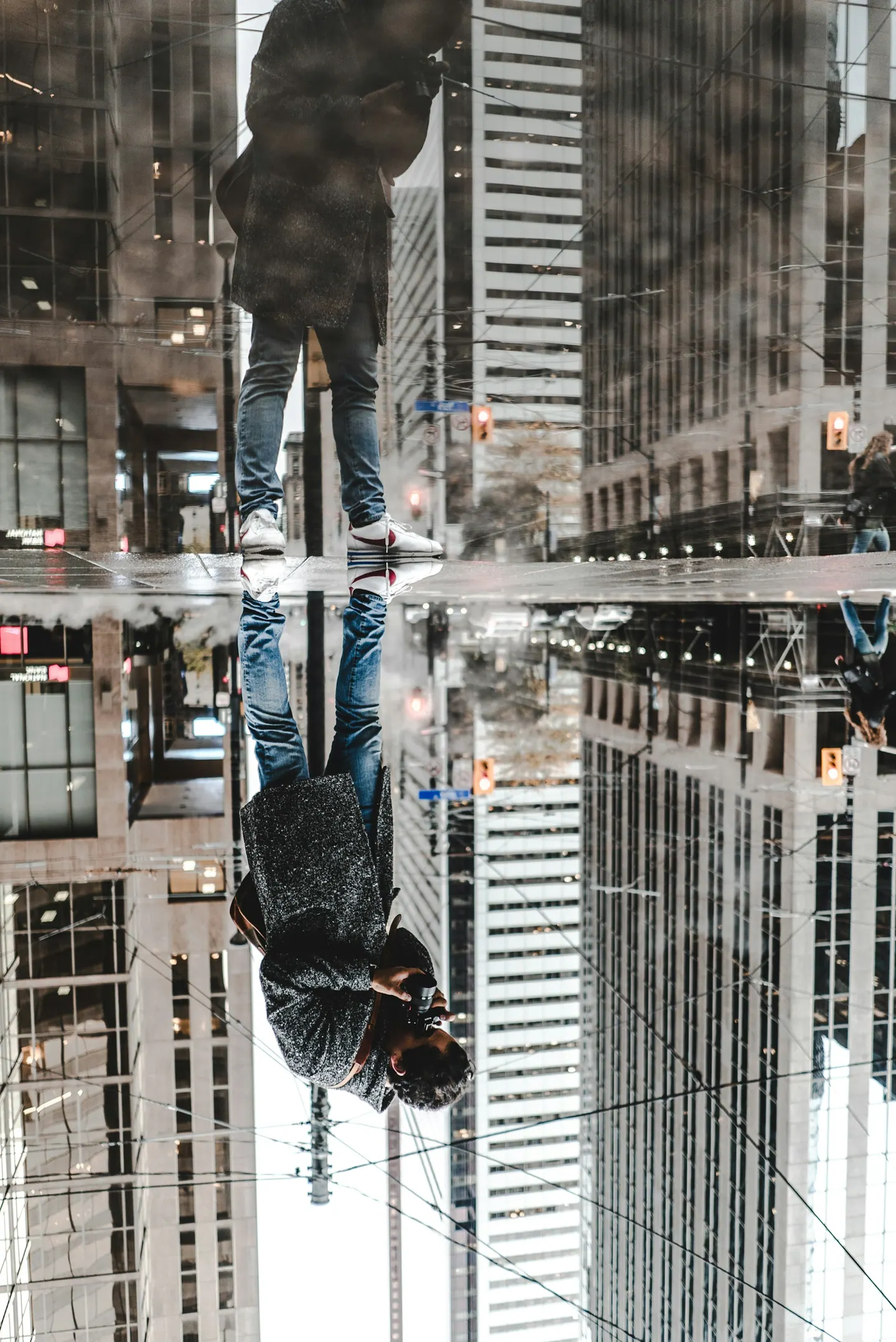 Reflexo na água de um homem de pé diante de prédios